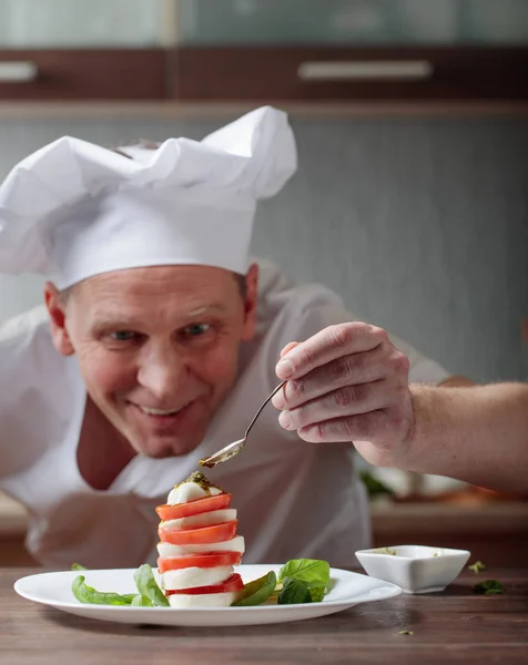 Chef prepares a snack with mozzarella and pesto sauce . — Stock Photo, Image