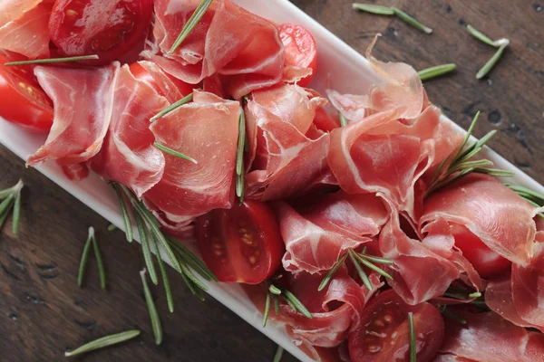 Prosciutto med rosmarin och tomat . — Stockfoto