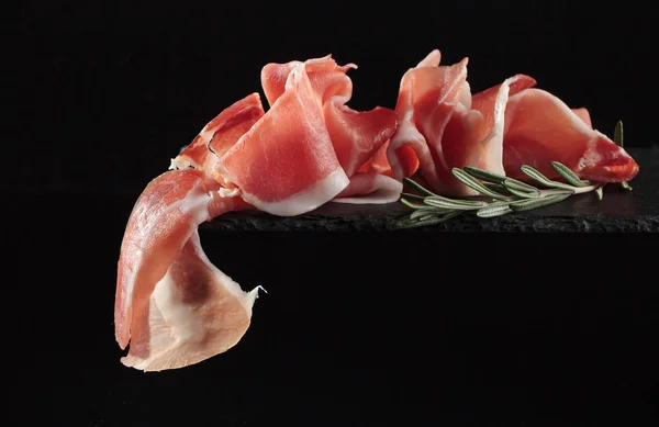 Prosciutto sobre fondo negro . —  Fotos de Stock