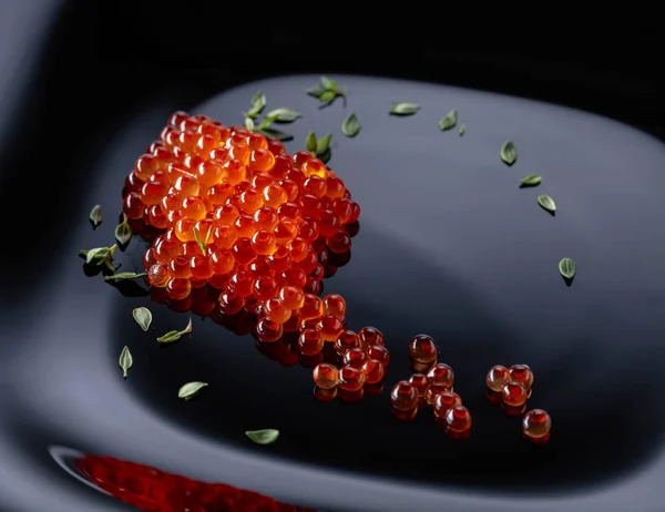 Red caviar on a black plate. — Stock Photo, Image