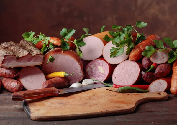 Different sausages and smoked meats on a  wooden table . — Stock Photo, Image