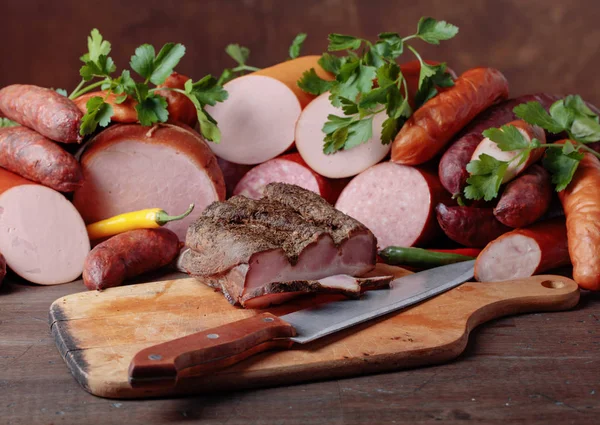 Different sausages and smoked meats on a  wooden table . — Stock Photo, Image