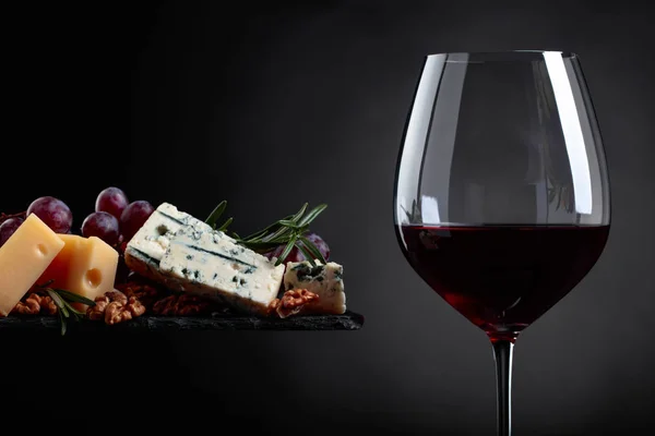 Glas Rotwein mit verschiedenen Käsesorten, Trauben und Walnüssen . — Stockfoto