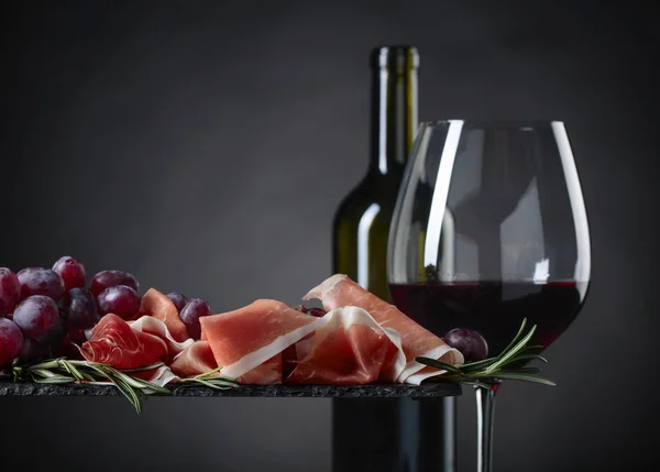 Prosciutto com alecrim e copo de vinho tinto . — Fotografia de Stock