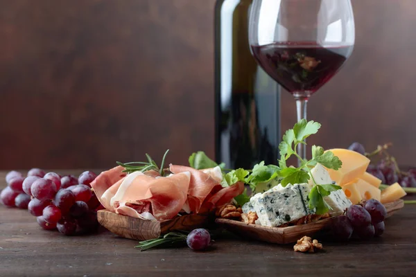 Pohár vörös bor különböző sajtok, gyümölcsök és prosciutto . — Stock Fotó