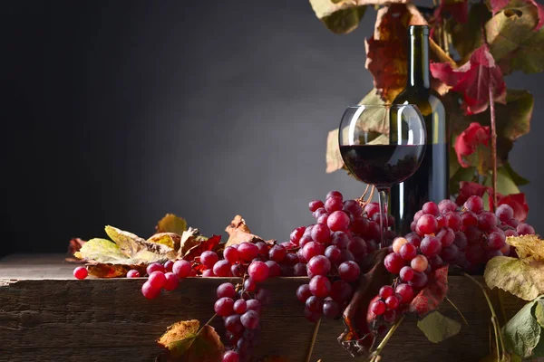 Rött vin och druvor på ett gammalt träbord . — Stockfoto