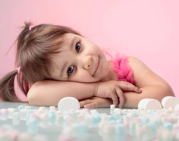 Portrait of a cute little girl with marshmallow on pink backgrou — Stock Photo, Image