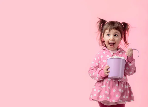 Cute little girl holding small violet bucket of marshmallow. — Stock Photo, Image