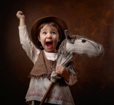 Sevimli küçük kız ev yapımı h ile oynarken bir kovboy gibi giyinmiş