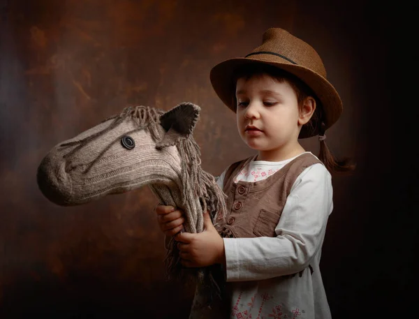 Милая маленькая девочка, одетая как ковбой, играющая с домашним h — стоковое фото