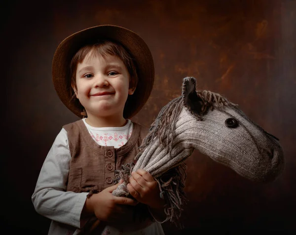 Cute little girl dressed like a cowboy playing with a homemade h — Stock Photo, Image