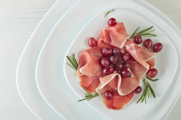 Jamon serrano with rosemary and grape . — Stock Photo, Image