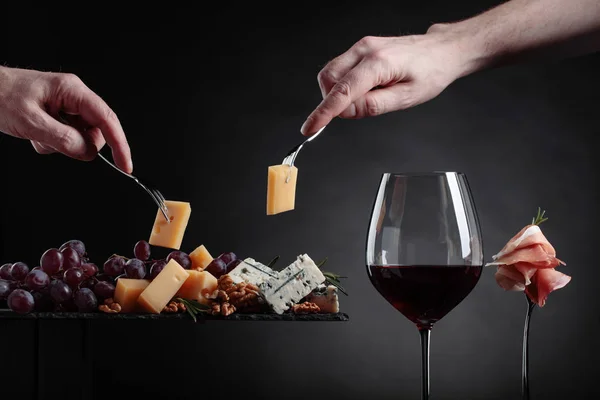 Copo de vinho tinto com vários queijos, frutas e presunto . — Fotografia de Stock