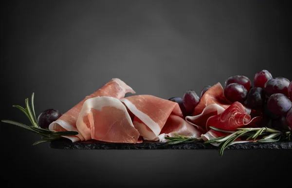 Prosciutto with grapes and rosemary . — Stock Photo, Image