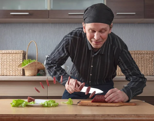 Чоловік з ножем розрізає шматки ковбаси . — стокове фото
