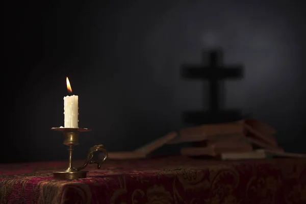Lumânare pe un fundal întunecat cu silueta crucii . — Fotografie, imagine de stoc
