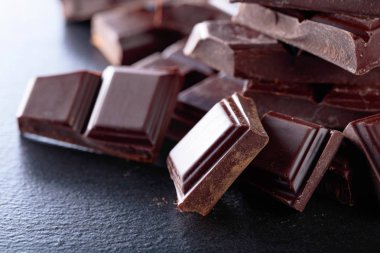 Siyah arka plan üzerine kırık çikolata parçaları.