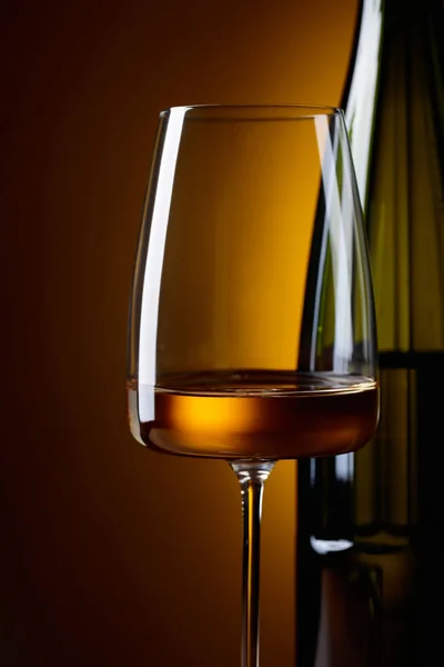 Glas och en flaska vitt vin på gul bakgrund. — Stockfoto