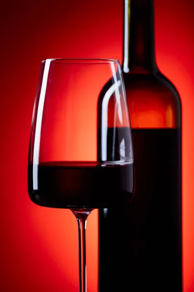 メガネと赤い背景の上の助言のワインのボトル. — ストック写真
