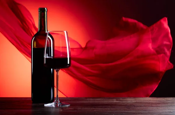 Gläser und eine Flasche Wein auf rotem Grund. rot schiere f — Stockfoto