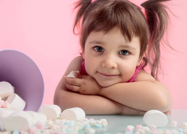 Portrait of a cute little girl with marshmallow on pink backgrou — Stock Photo, Image