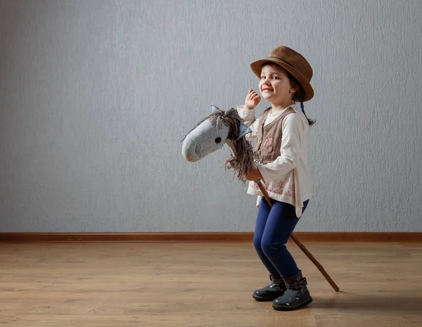 Cute little girl dressed like a cowboy playing with a homemade h — Stock Photo, Image