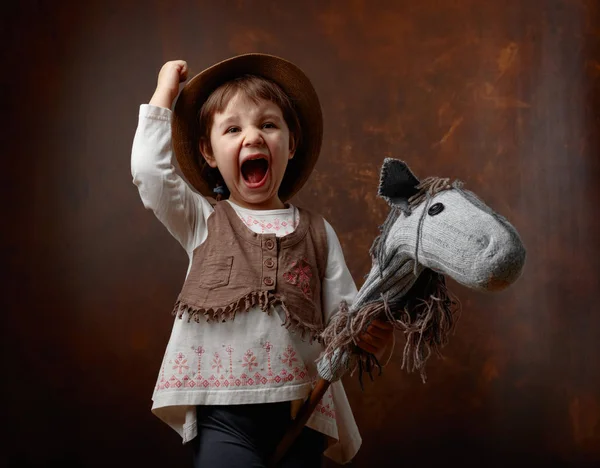 Cute little girl dressed like a cowboy playing with a homemade h — Stock Photo, Image