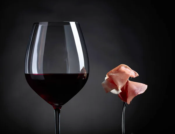 Glass of red wine with prosciutto and rosemary. — Stock Photo, Image