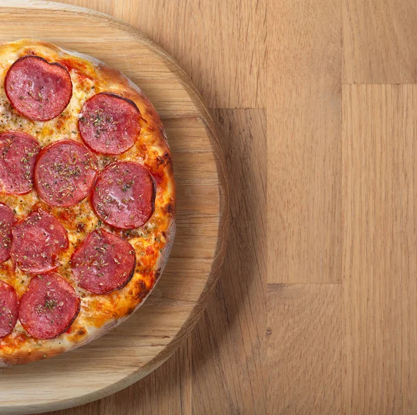 Fresh backed pizza with salami on a wooden board. — Stock Photo, Image