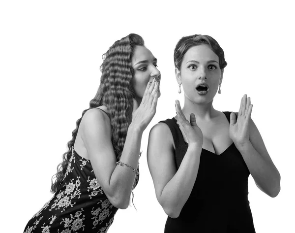 Duas jovens mulheres sussurrando fofocas no fundo branco . — Fotografia de Stock