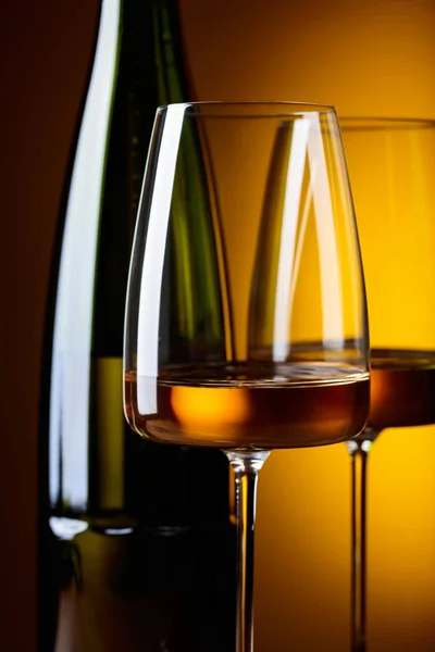 Sklenice a láhev bílého vína na žlutém podkladu. — Stock fotografie