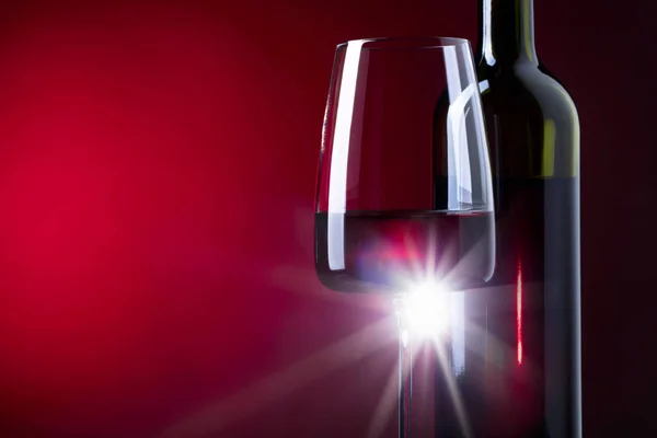 Bicchiere e bottiglia di vino rosso su sfondo scuro . — Foto Stock
