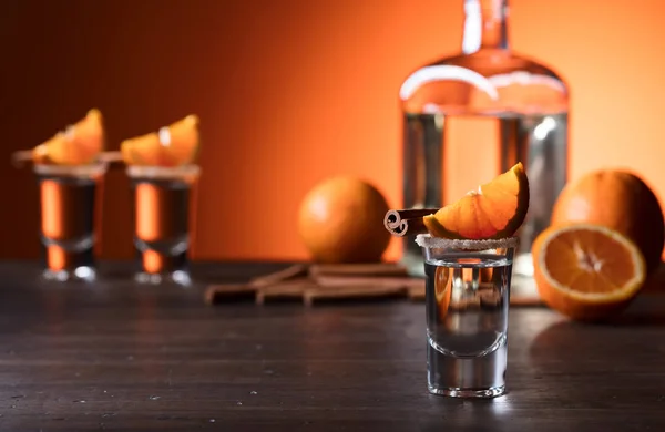 Vasos de tequila con palitos de naranja y canela en una t de madera —  Fotos de Stock