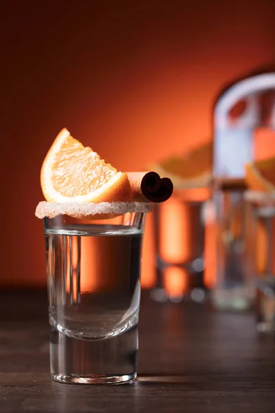 Tequila-Gläser mit Orangen- und Zimtstangen auf einem Holz-T — Stockfoto