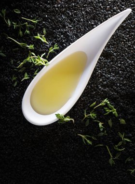 Bitki Yağ kekik dalları bir arka plan üzerinde siyah susam ile.