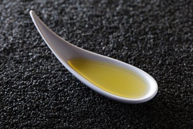 Susam yağı küçük kase bir arka plan üzerinde siyah susam. 