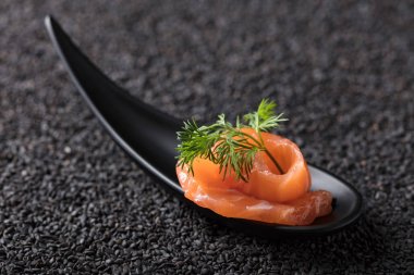 Siyah susam arka plan üzerine dereotu ile tuzlanmış somon.