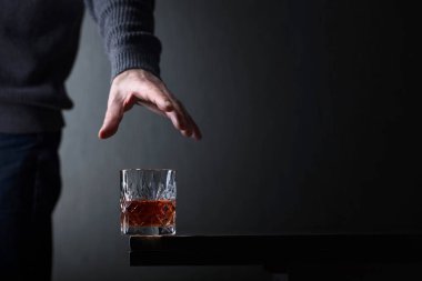 Bir bardak alkol için elini ulaşır.