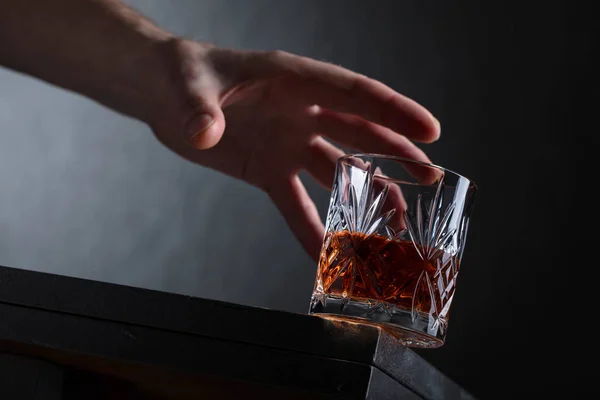 Mužova ruka dosáhne na sklenku alkoholu. — Stock fotografie