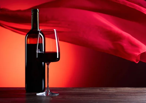 メガネと赤い背景の上の助言のワインのボトル。赤の薄い f — ストック写真