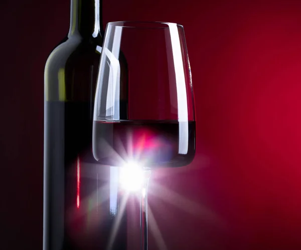 Glass and bottle of red wine on dark background. — Stock Photo, Image