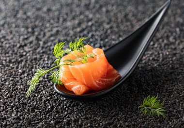 Siyah susam arka plan üzerine dereotu ile tuzlanmış somon.