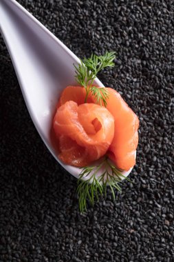 Siyah susam arka plan üzerine dereotu ile tuzlanmış somon.