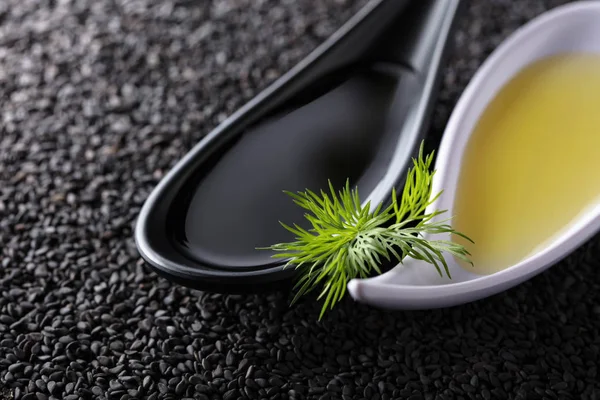 Vegetabilisk olja med dill grenar på en bakgrund av svarta sesamfrön. — Stockfoto