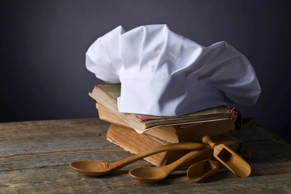 Παλιά βιβλία μαγειρικής, καπέλο σεφ και ξύλινα κουτάλια . — Φωτογραφία Αρχείου