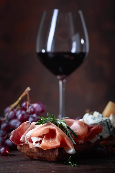 Prosciutto met rozemarijn en glas rode wijn  . — Stockfoto