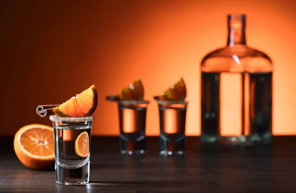 Tequila-Gläser mit Orangen- und Zimtstangen auf einem Holz-T — Stockfoto