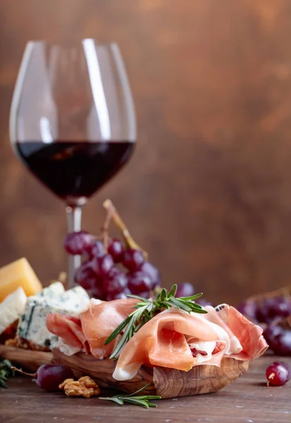 Copa de vino tinto con varios quesos, frutas y jamón  . — Foto de Stock