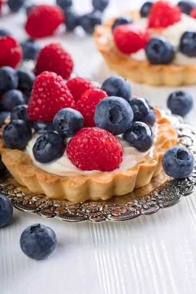 Tartas de postre con frambuesas y arándanos en una mesa de madera — Foto de Stock