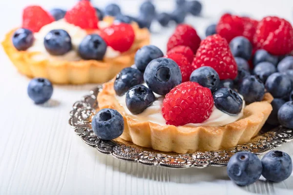 Десертные пироги с малиной и черникой на деревянной доске — стоковое фото